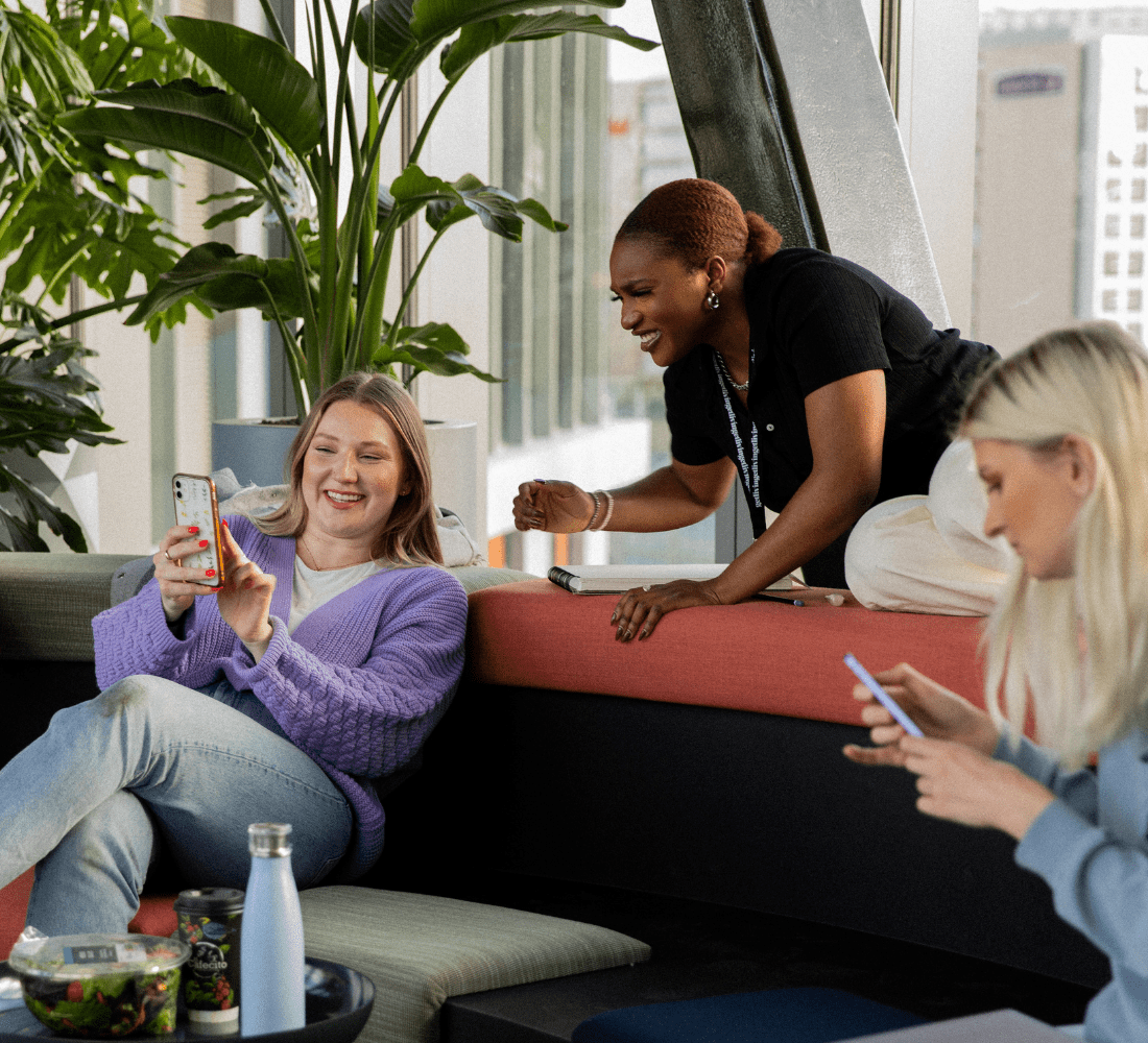 A group of friends showing each other something on their phone in the communal Skybridge at Portlands Place