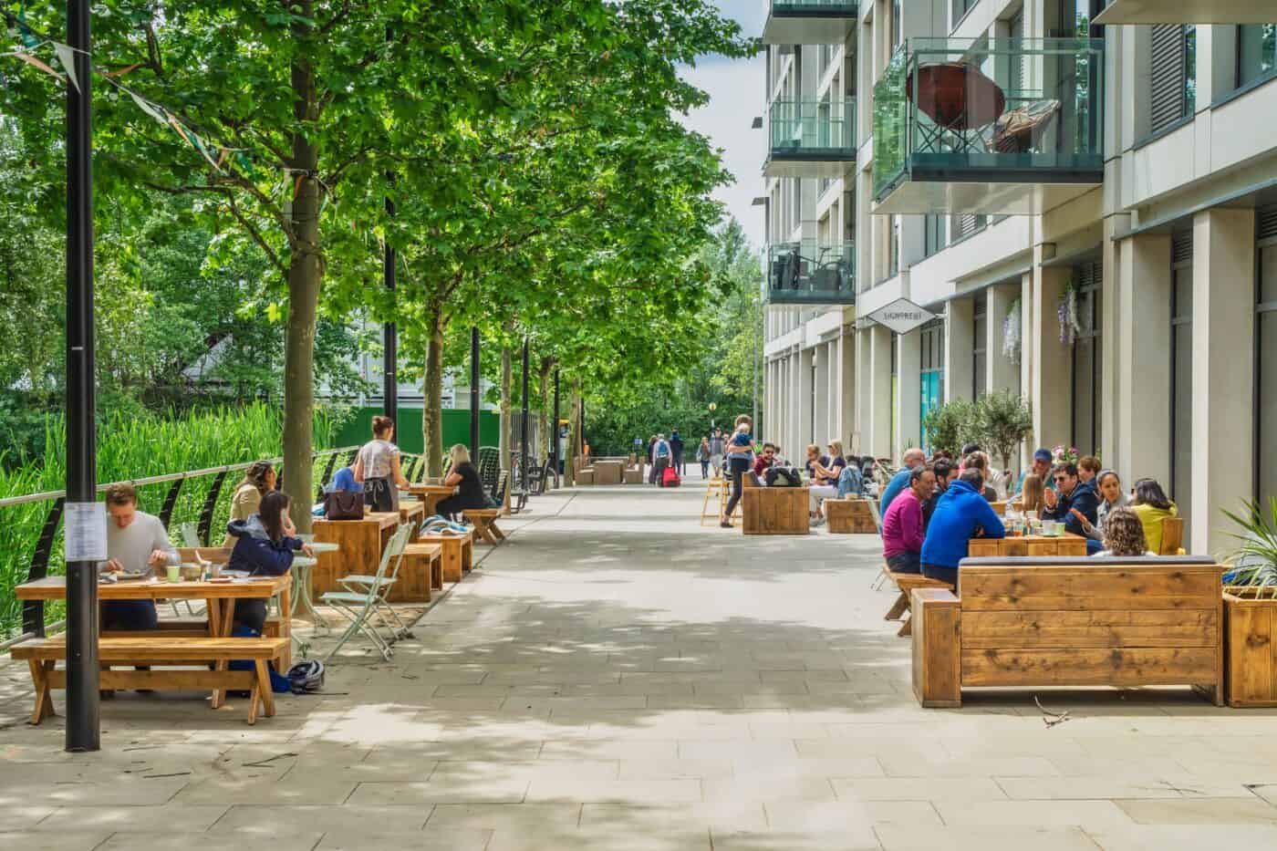 A summer's day on Victory Parade in East Village with people sat outside eating and drinking at the local cafes