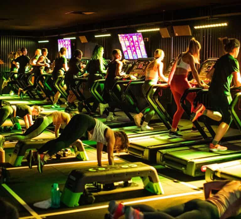 A packed workout class on treadmills and doing strength exercises